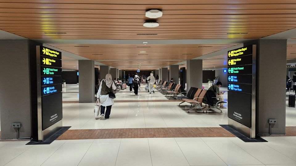 A bright airport arrivals hall with information screens