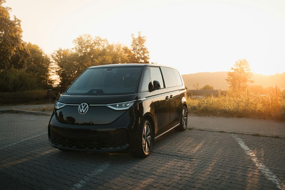 A black minivan parked on an empty road at sunset