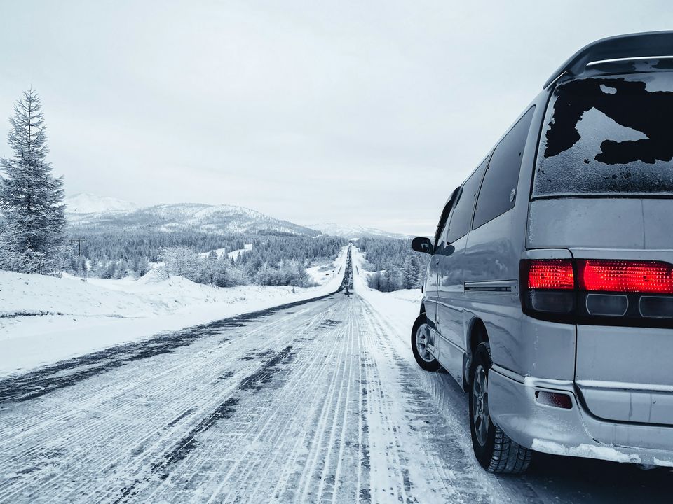A silver minivan on an icy road through a snowy landscape