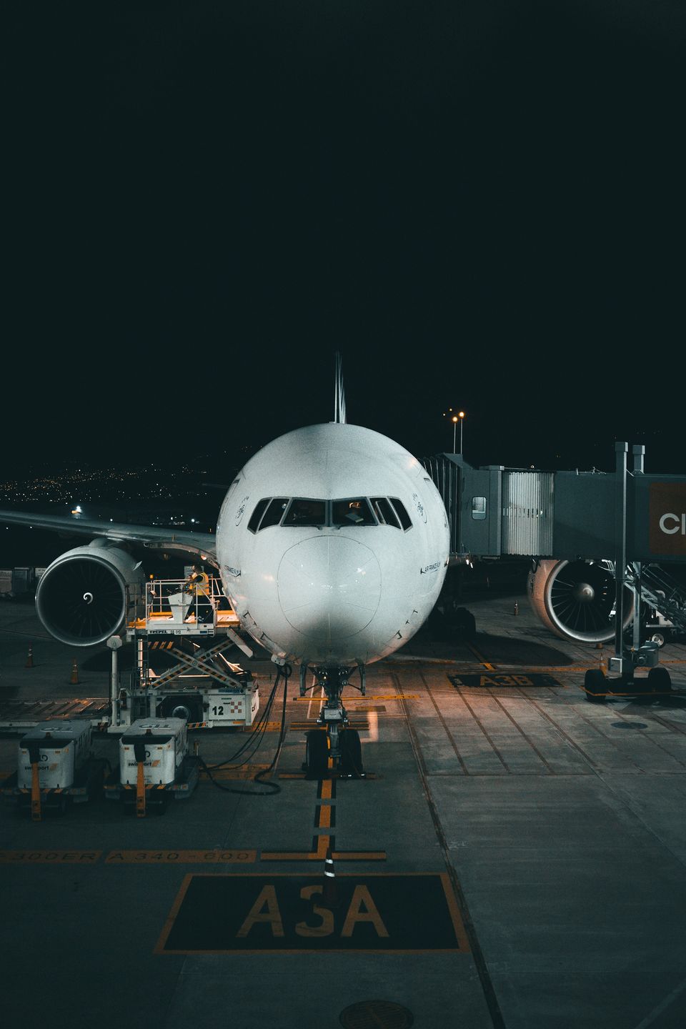 A passenger jet parked nose-in at an airport gate at night