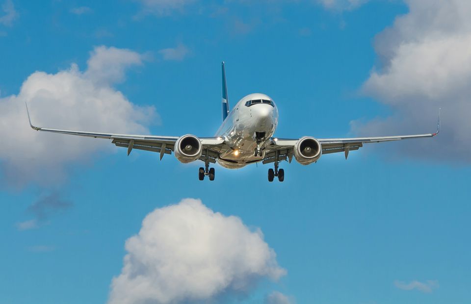 A passenger jet coming in to land, wheels down, against a blue sky with white clouds