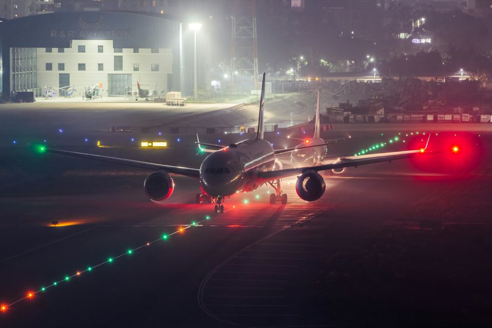 A jet taxiing at night between green and red runway lights