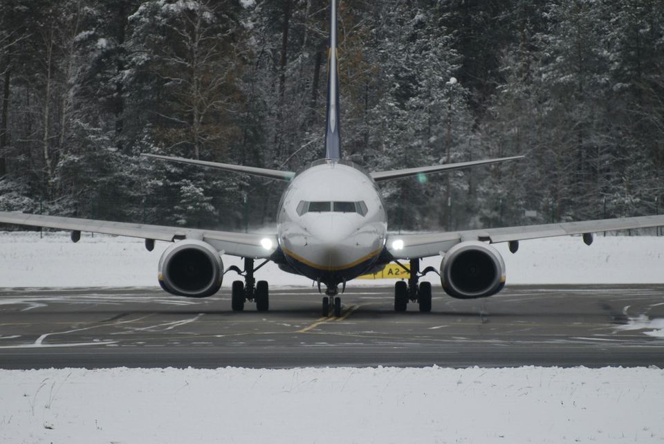 A passenger jet on a snowy runway in front of snow-covered spruce forest