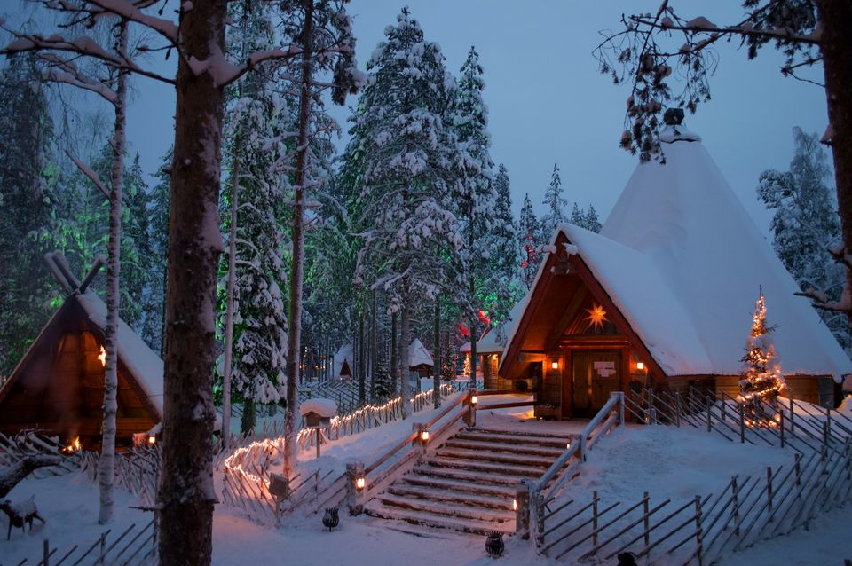 Snow-covered wooden cabins with warm lights at Santa Claus Village