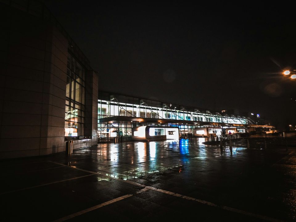 An airport terminal lit up at night beside a wet apron