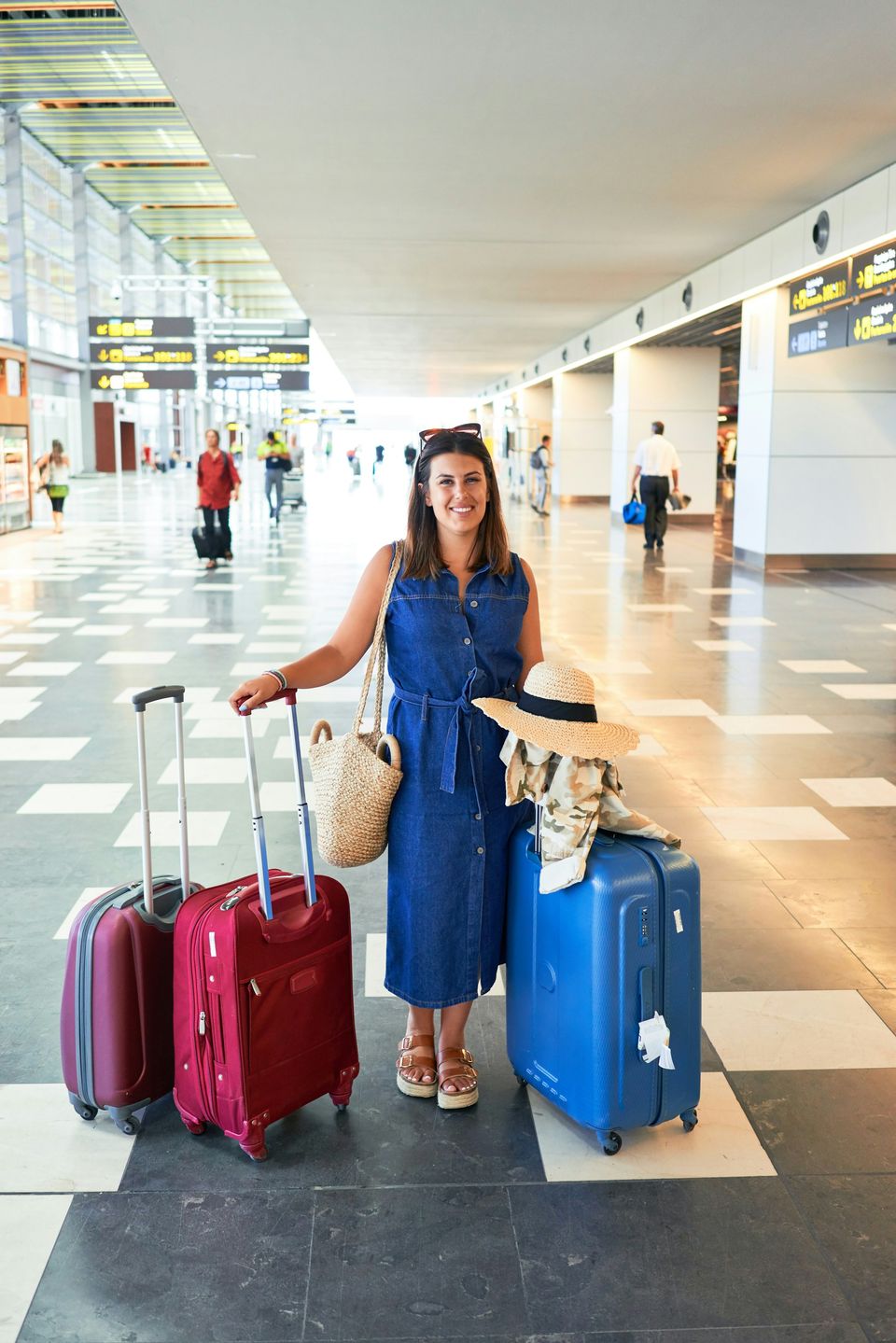 A smiling traveller with two suitcases in an airport terminal