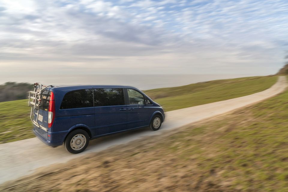 A blue Mercedes-Benz van driving along a country road