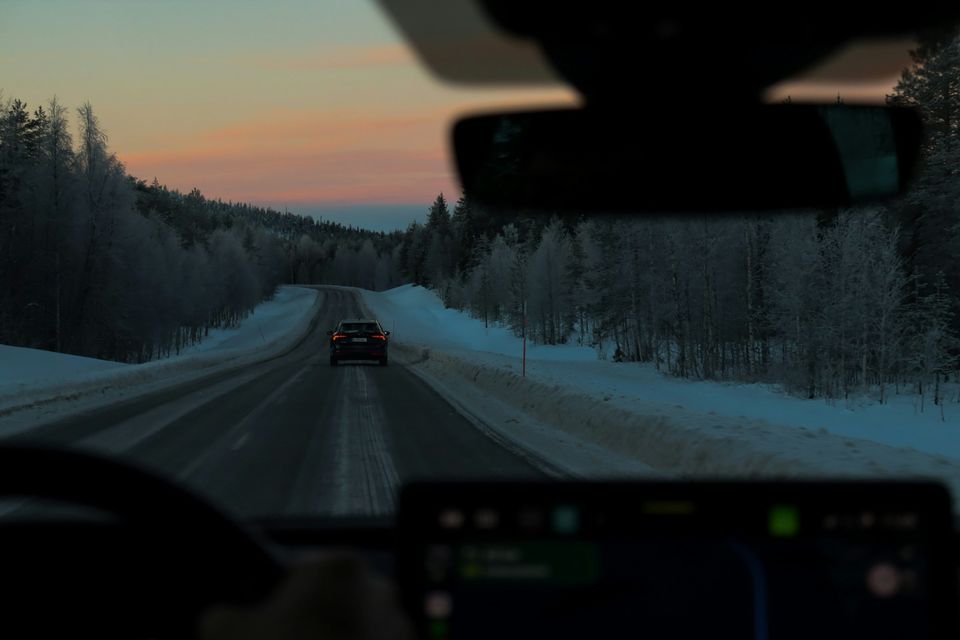 The view through a windscreen of a snowy forest road at dusk